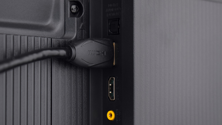 Close-up of an HDMI cable being inserted into a port on the back of a television.