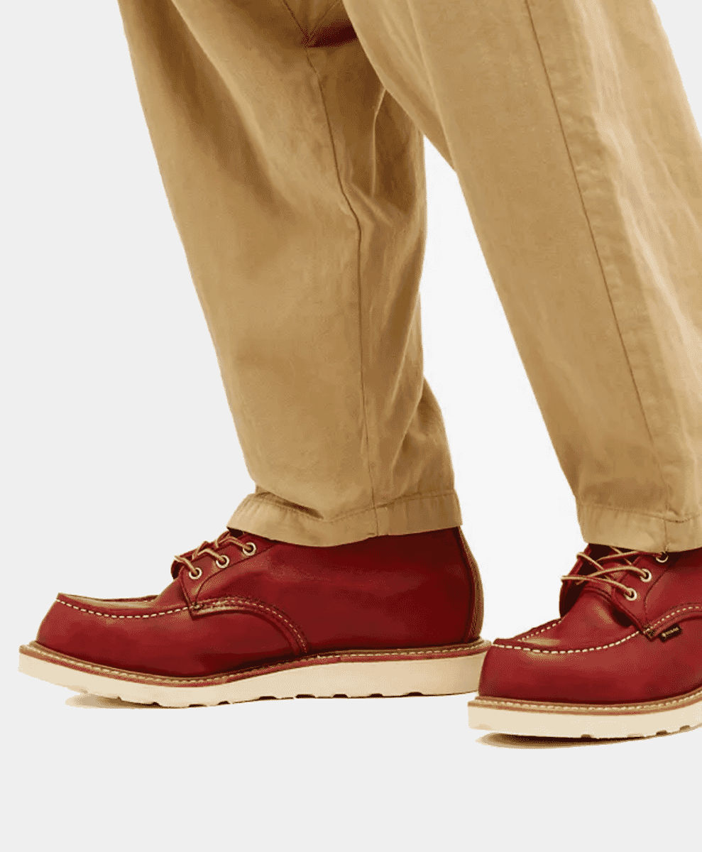 Close-up of a person wearing red moc-toe boots with beige chinos.