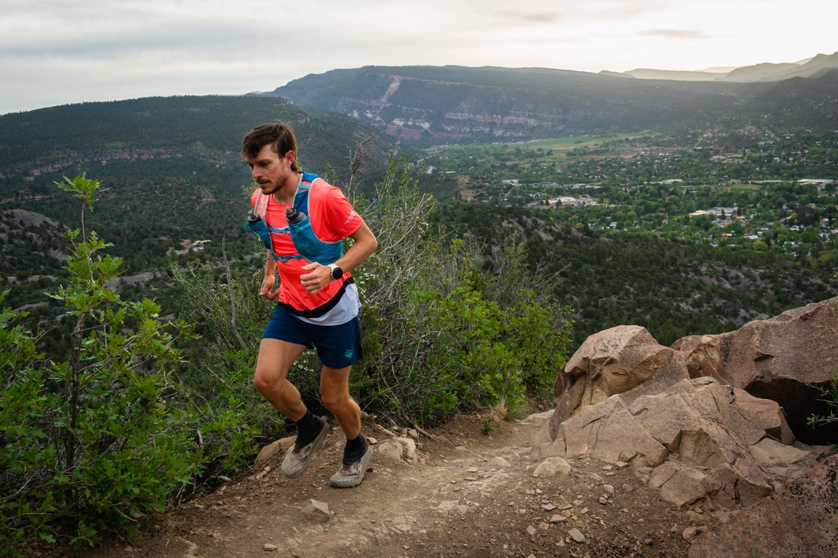 A runner wearing Dirty Girl Gaiters while running through a forest trail in Colorado.