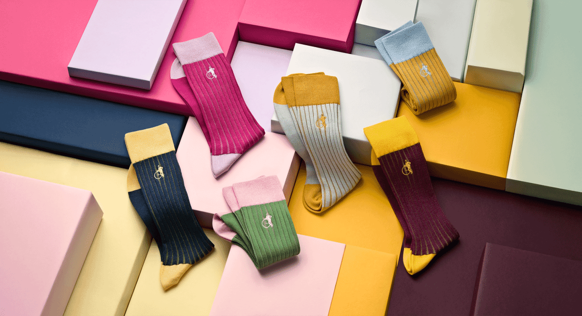 Colorful ribbed socks displayed on geometric pastel and bold-colored boxes.