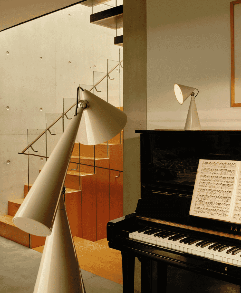 White Tom Dixon Pose Task Lamps placed next to a black upright piano.