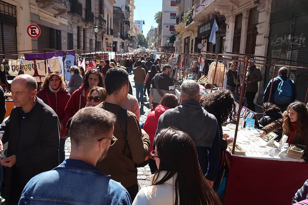 Crowds of people browsing antique stalls and crafts at the outdoor Feria de San Telmo market.