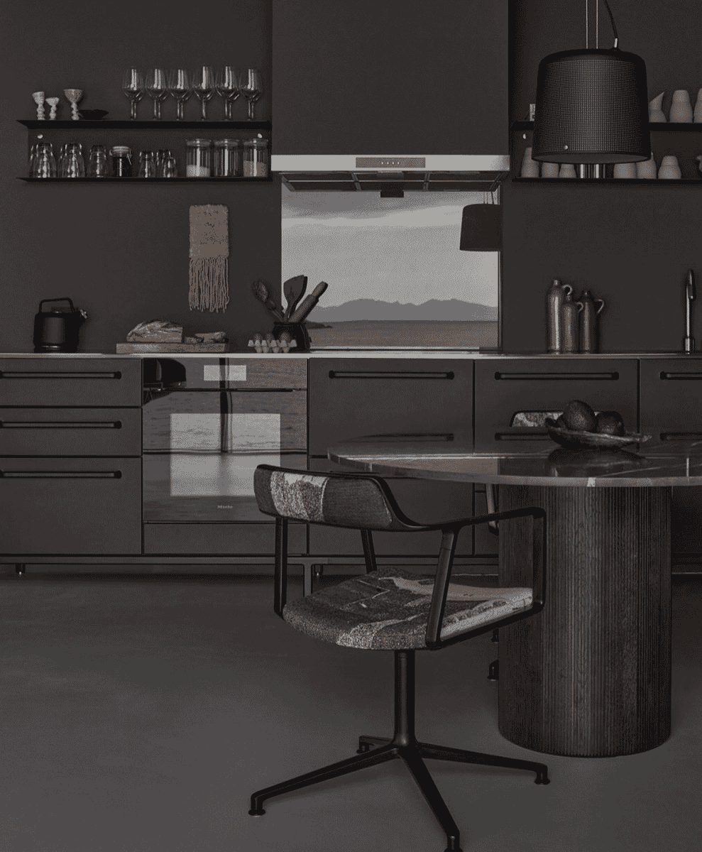 A minimalist kitchen with dark cabinetry and contemporary dining furniture.