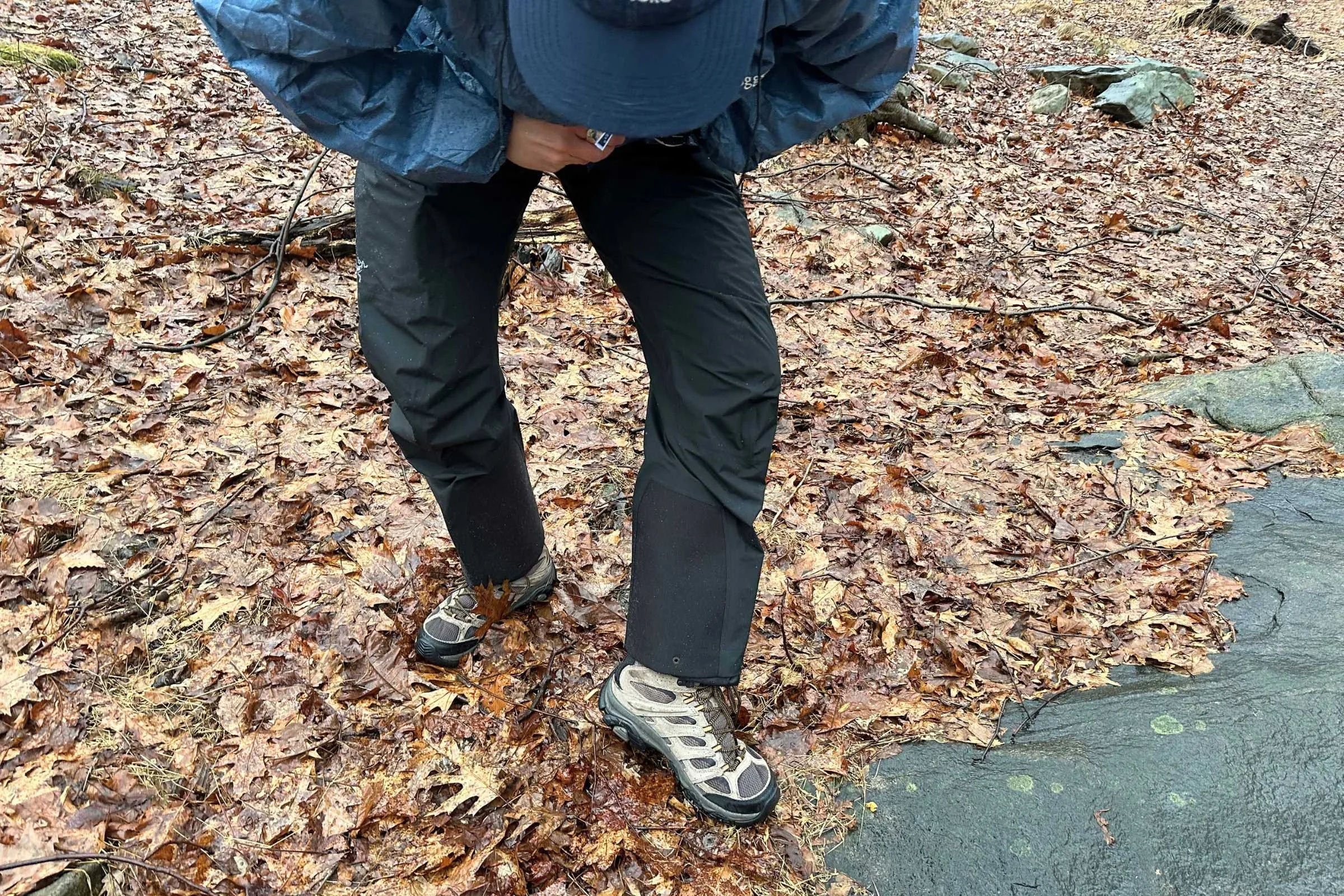Full body shot of a person wearing Arcâteryx Beta AR rain pants in a snowy forest.