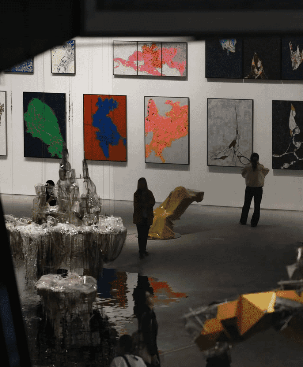 Visitors in casual attire exploring an art gallery featuring abstract paintings and contemporary sculptures.