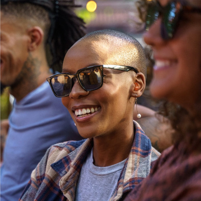 People in a social setting talking comfortably while wearing subtle earplugs.