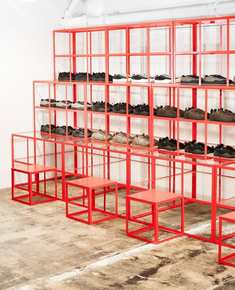 Minimalist retail interior featuring bold red metal shelving displays for sneakers.