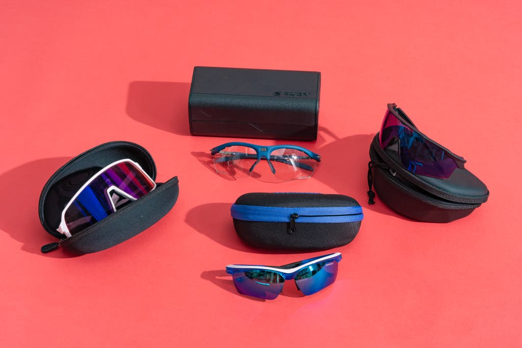 A collection of four different sports sunglasses and their protective cases on a neutral background.