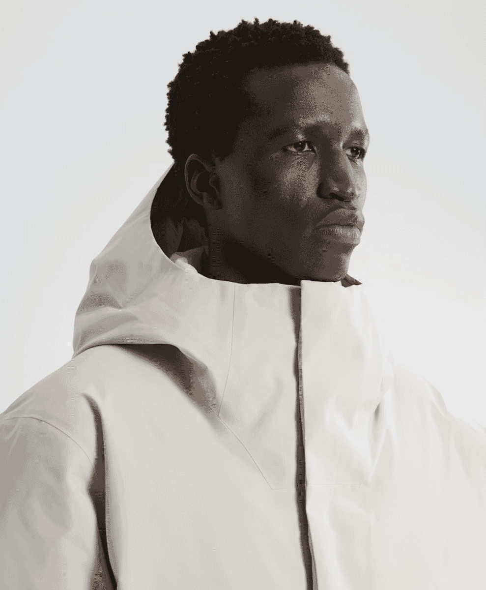 A man wearing a white structured hooded jacket against a white background.