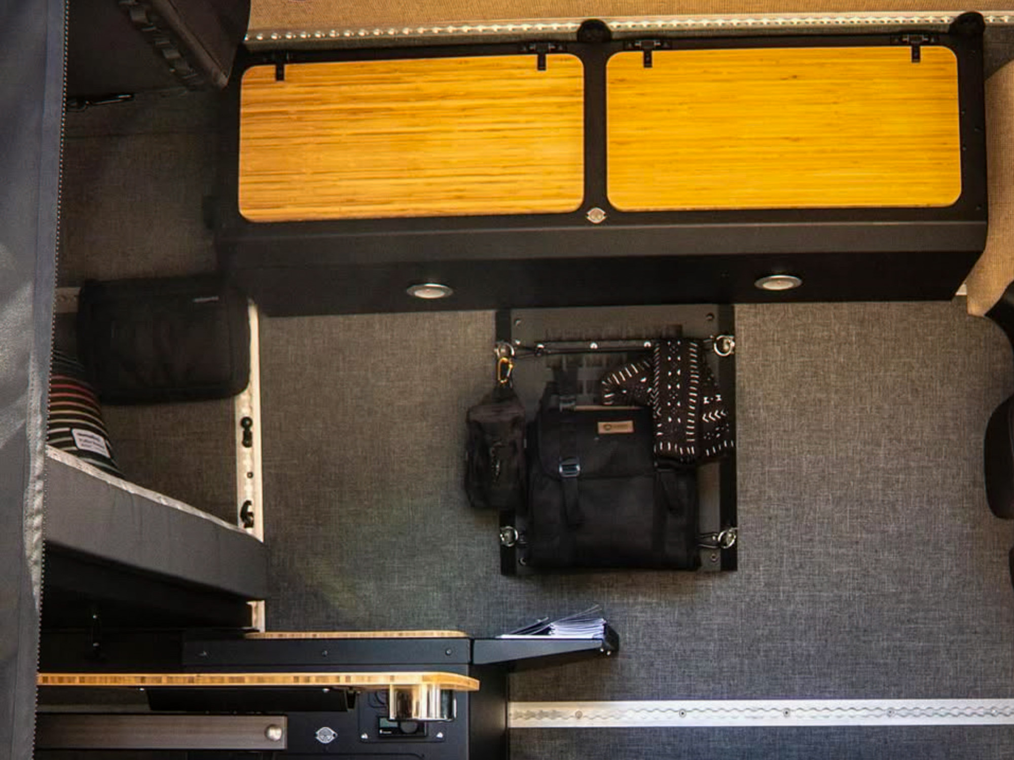Van interior showing modular cabinets and a bed frame securely bolted to an integrated L-track system.