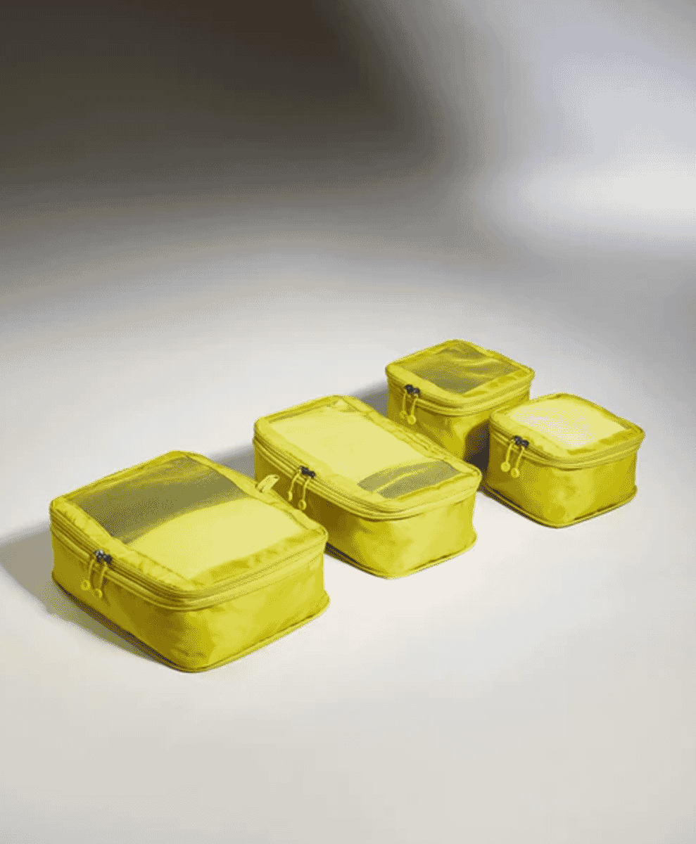Four bright yellow packing cubes arranged in a row to demonstrate organized packing.