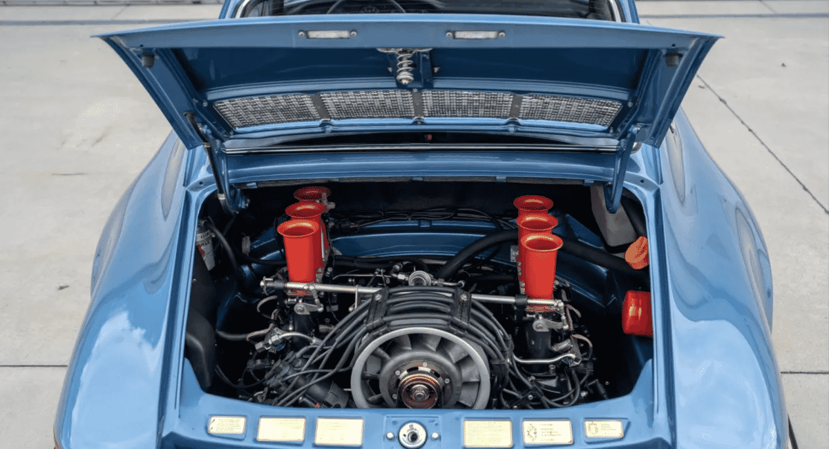 Engine bay of the blue Porsche 911 with distinct red air intakes.