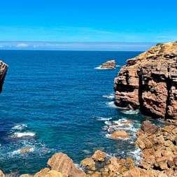 Rugged red sandstone cliffs and sea stacks being hit by Atlantic waves at Carrapateira.