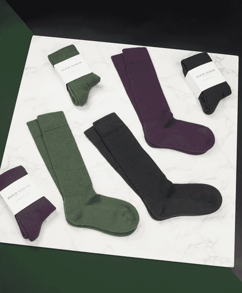 Multiple pairs of knee-high socks in earthy tones arranged on a marble surface.