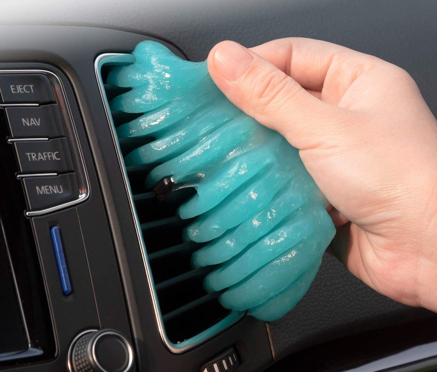 Cleaning putty being pressed into a car air vent to remove dust and debris.