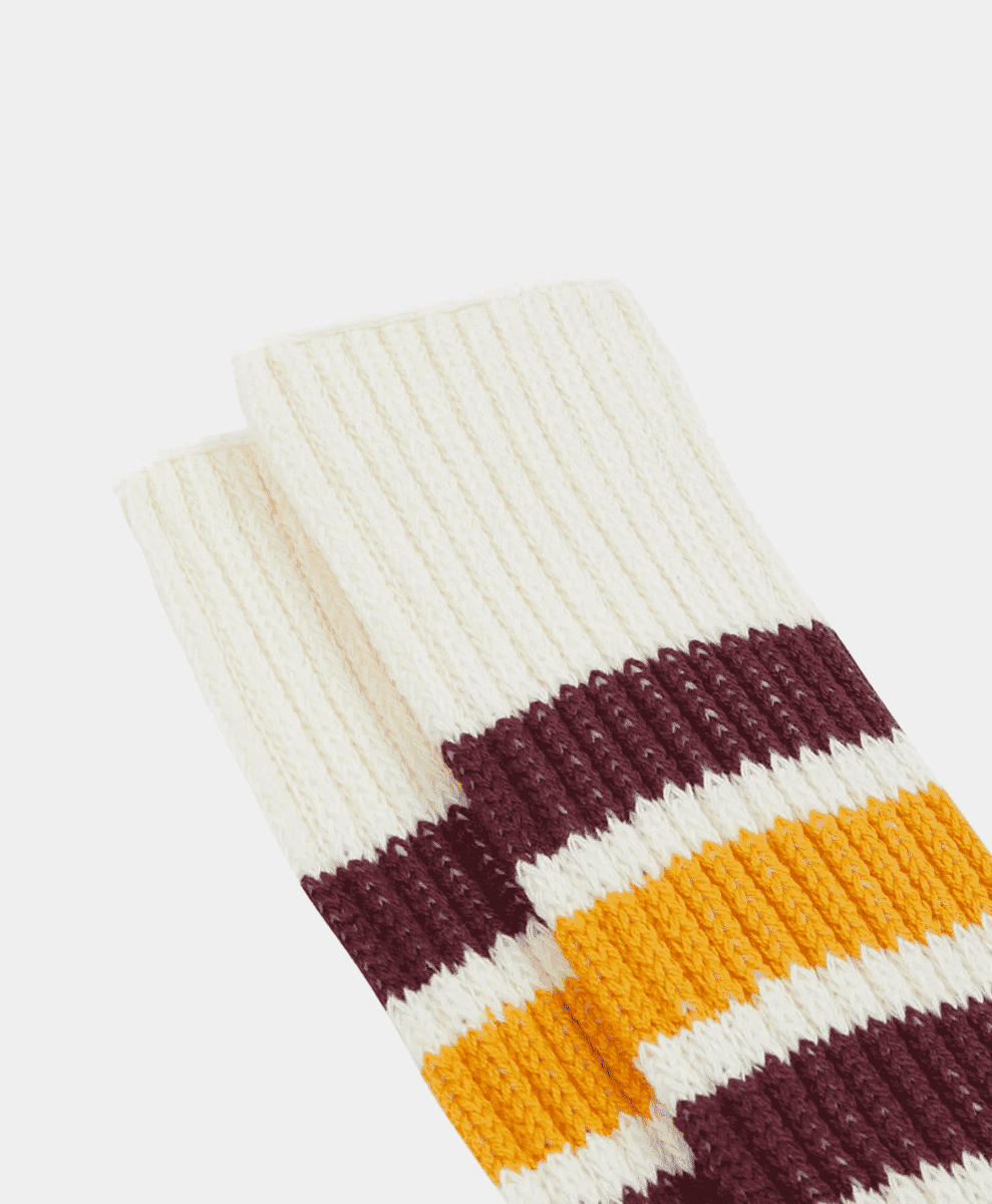 Close-up of ribbed crew socks with burgundy and mustard yellow horizontal stripes.
