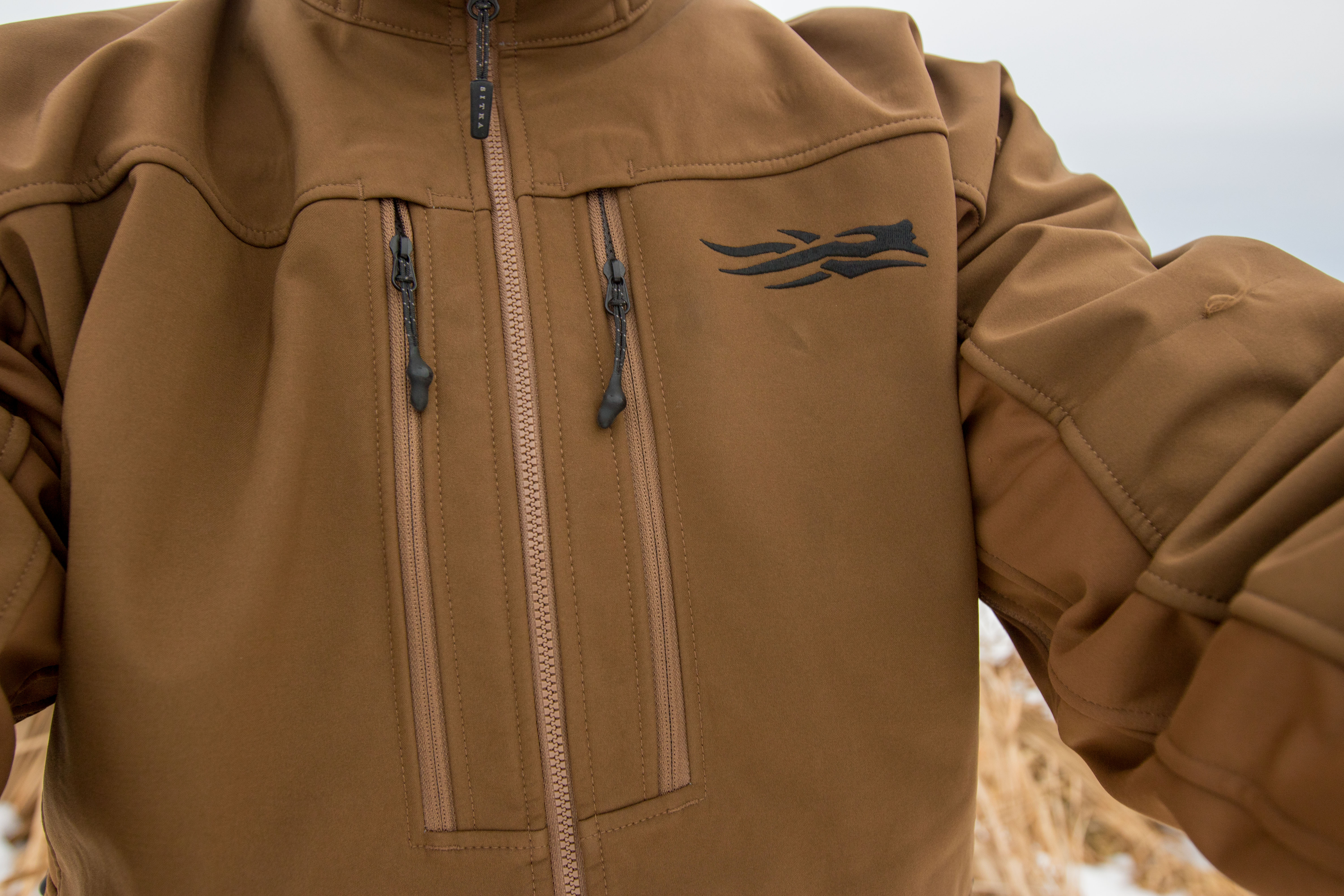 Detailed view of the SITKA logo and chest pocket zippers on the Jetstream jacket.