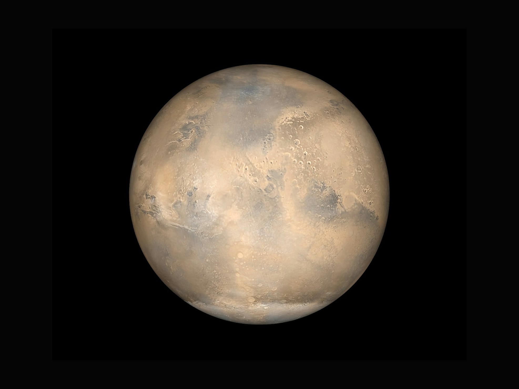 A wide-angle landscape shot of the dusty, red Martian surface under a hazy sky.