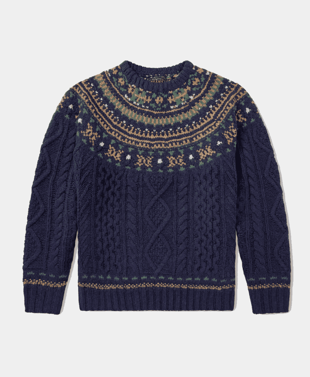 Flat lay of a navy blue Fair Isle knit sweater with green and white motifs.