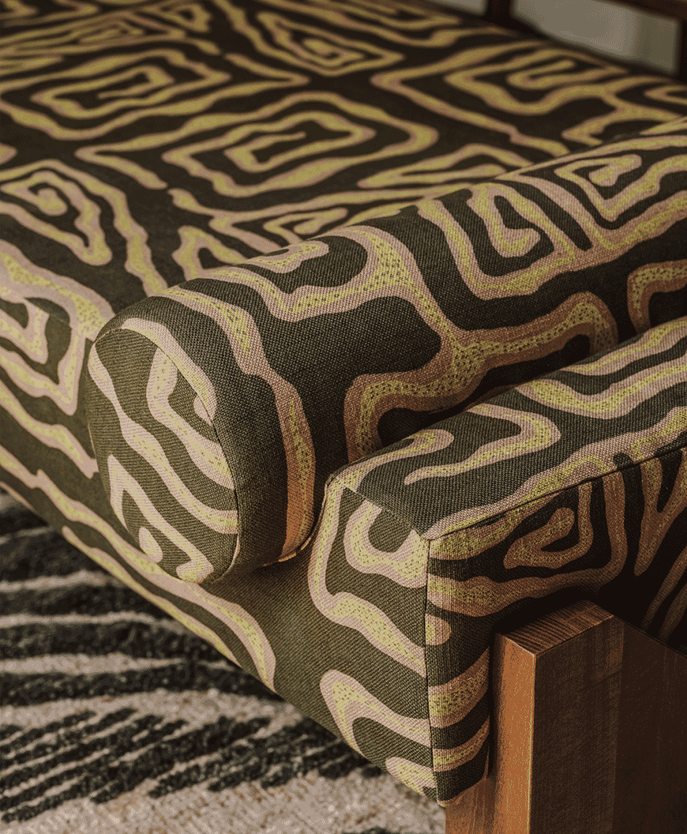 Detail of a modern sofa with bold olive green and beige geometric swirling patterns.