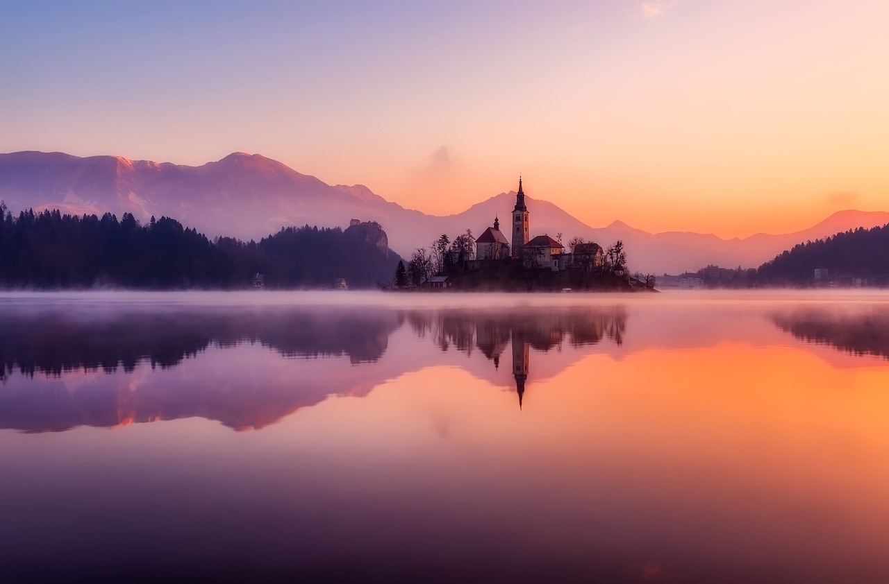The iconic church on the island in the middle of Lake Bled, Slovenia, surrounded by mountains.