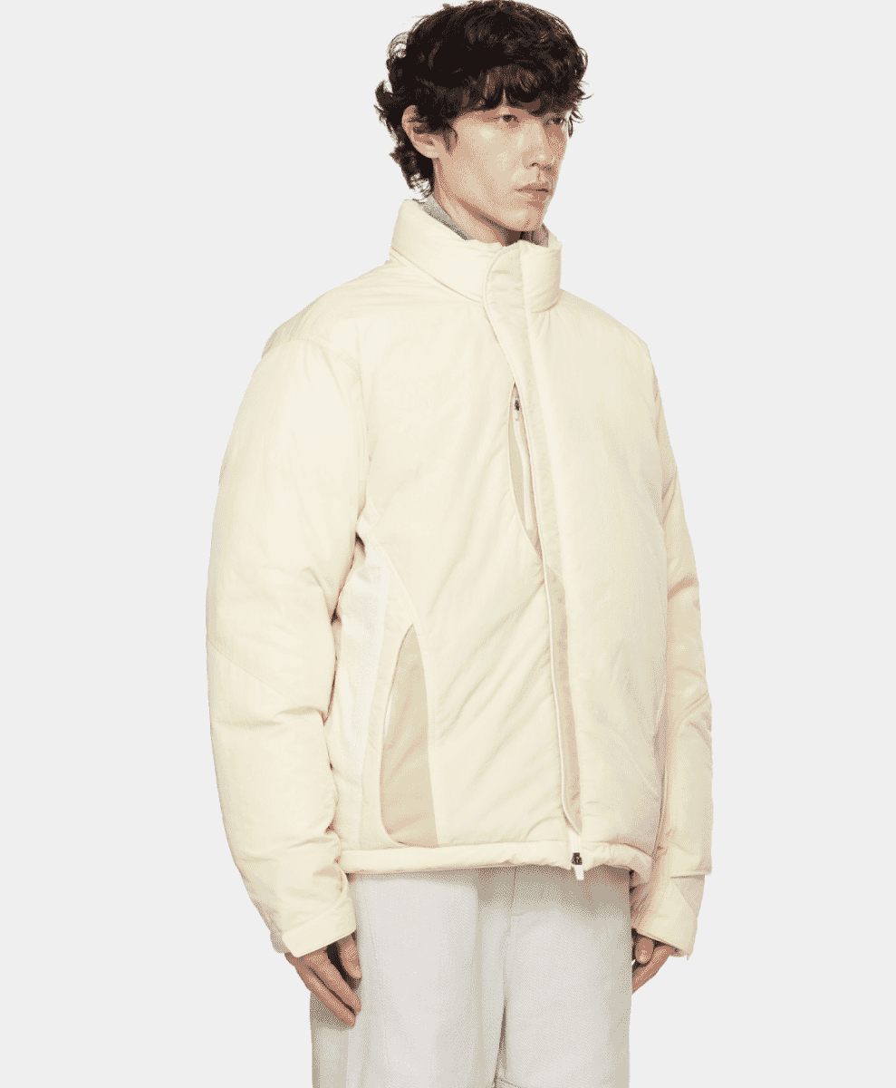 Model in an off-white puffer jacket with an asymmetrical zipper and high collar.