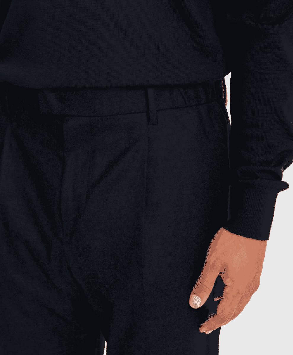 Close-up of black tailored trousers featuring an elastic waistband and pleated front.