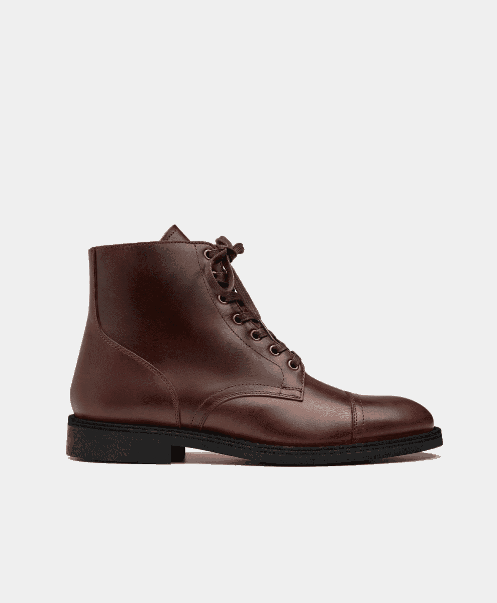 Side-profile of a brown leather lace-up ankle boot with a cap toe and black sole.