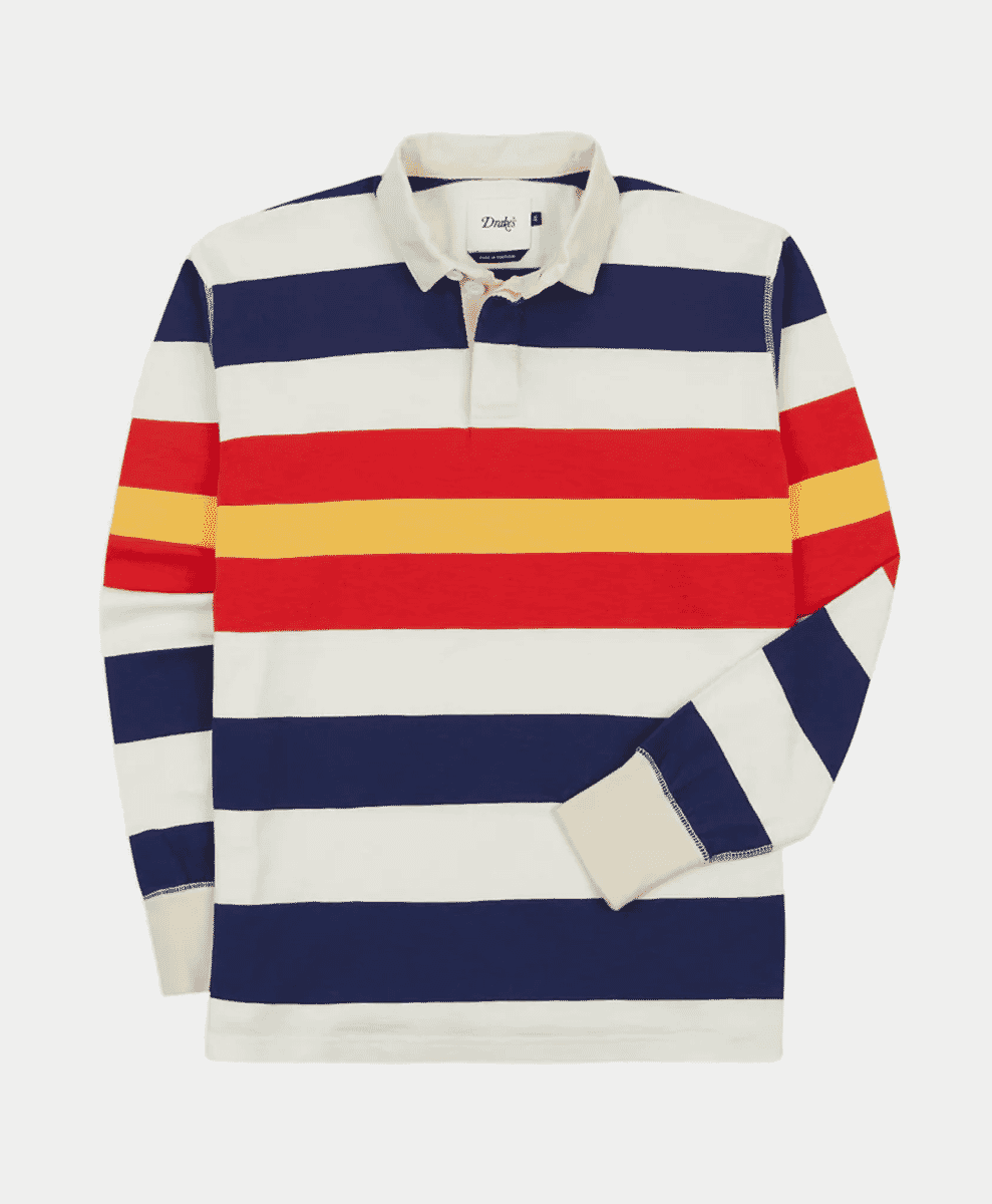 A long-sleeve Drake's rugby shirt with bold navy, white, red, and yellow horizontal stripes.