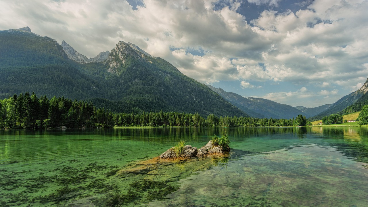 A calm blue lake reflecting tall pine trees and granite peaks during summer