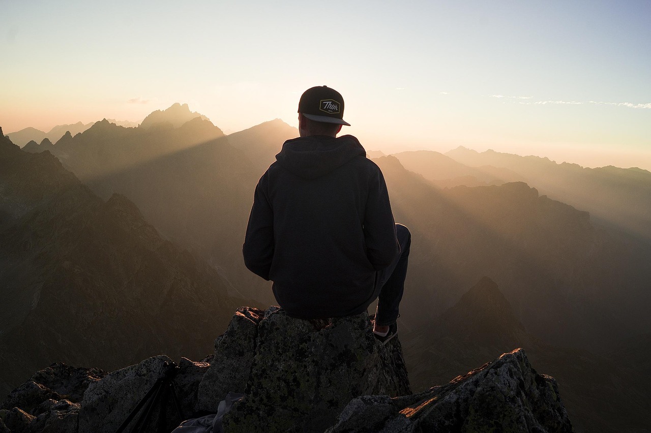 A person looking at a map while sitting on a rock overlooking a valley