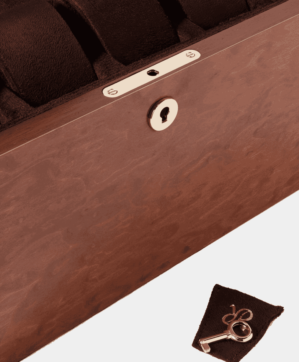 Detailed close-up of a brass lock and key on a polished wooden watch case.