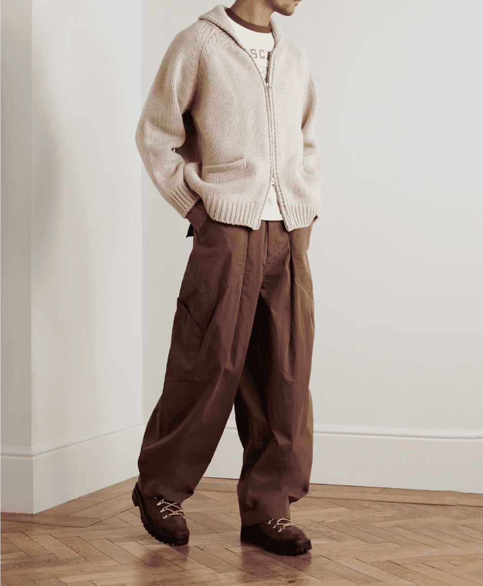 A man in a cream-colored hooded knit cardigan over a graphic tee.