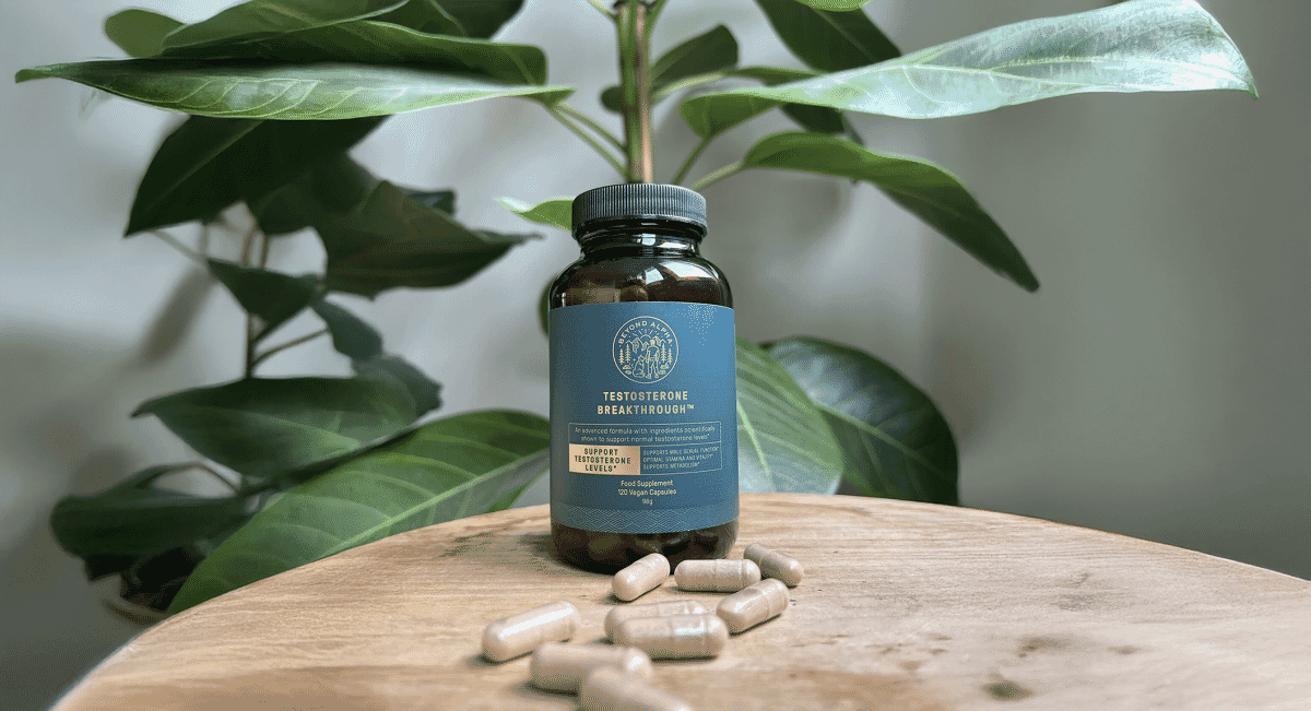 A supplement bottle on a rustic wooden surface surrounded by vibrant green foliage.