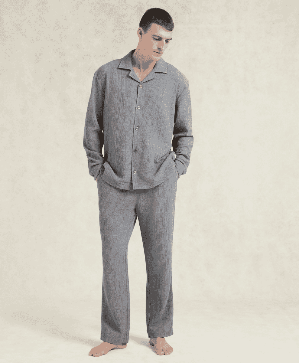 A man modeling a grey textured cotton cashmere pajama set against a neutral background.
