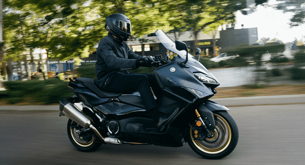 Rider in black gear on a black scooter in an urban environment