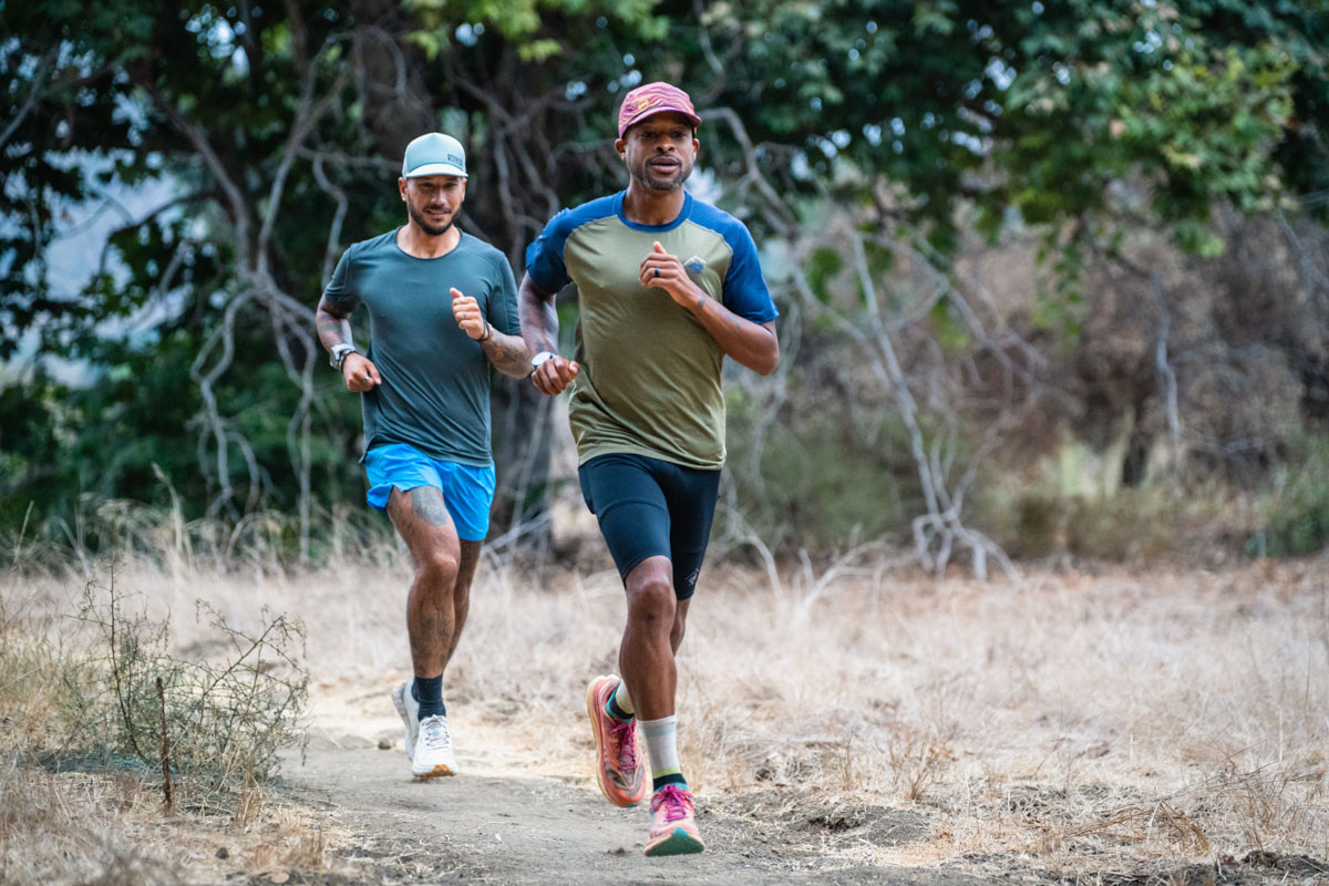 Two runners wearing crew-length socks while navigating a rocky trail.