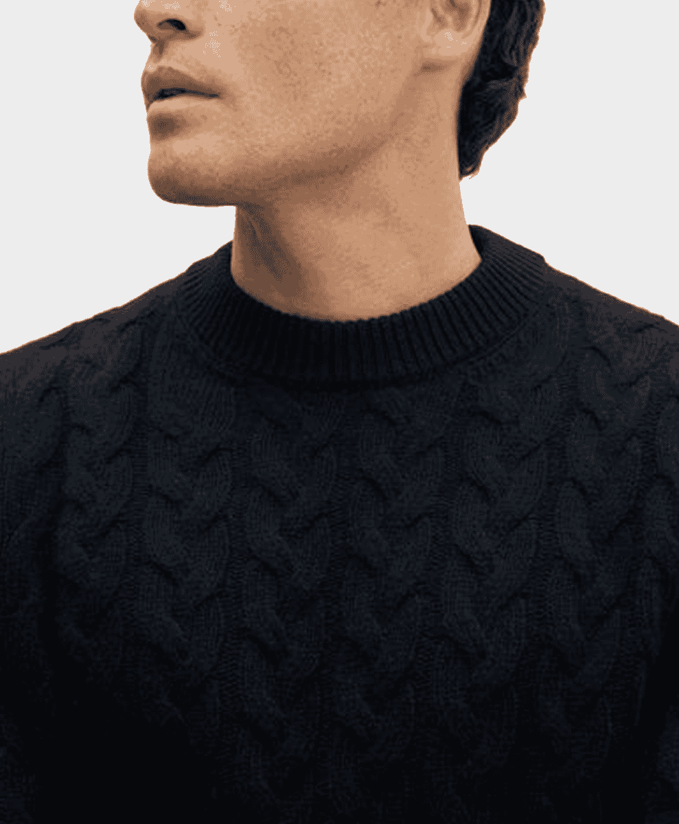 Close-up of black cable-knit sweater texture and ribbed crew neck.