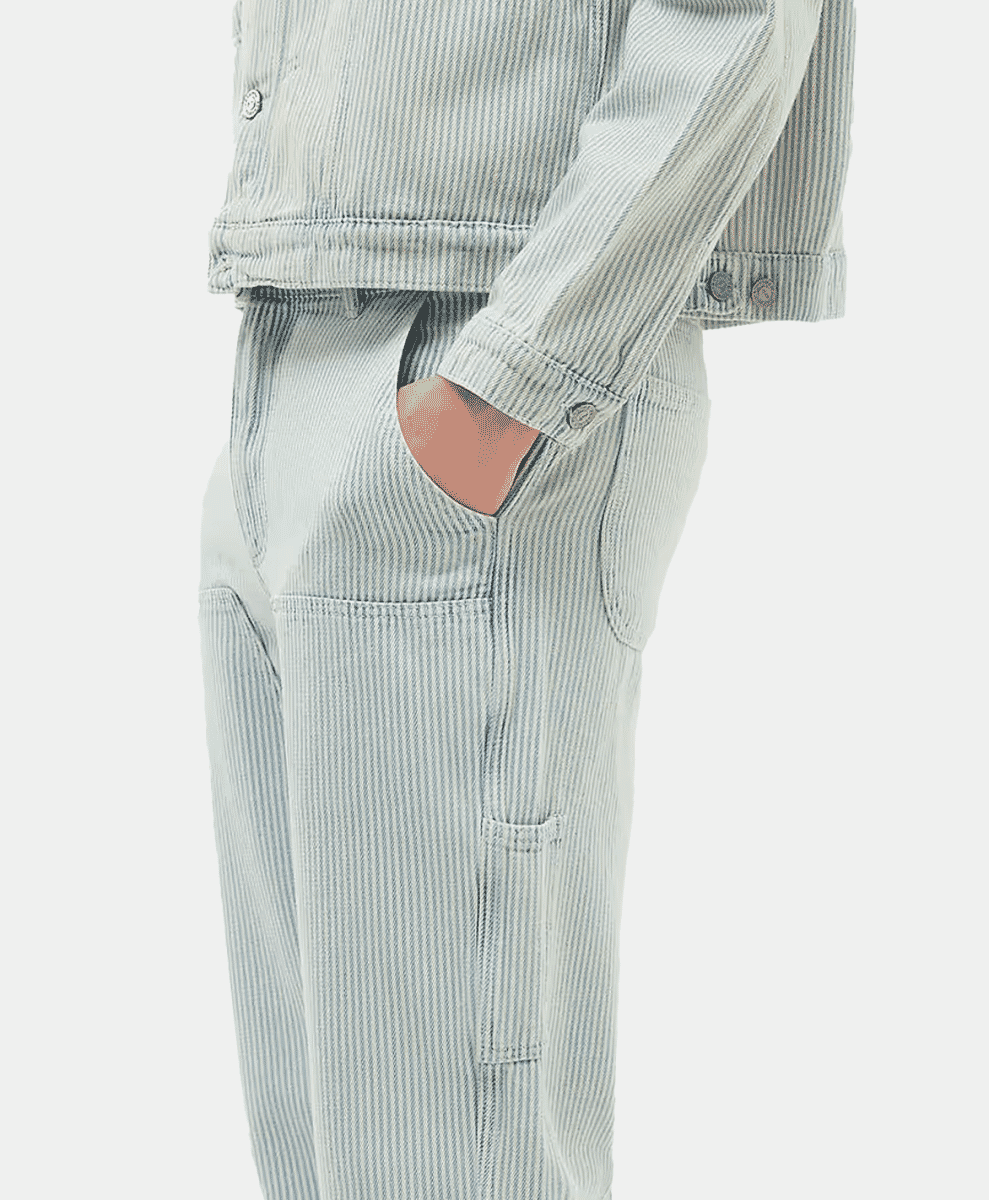 Model wearing a matching light blue and white hickory stripe denim jacket and trousers.