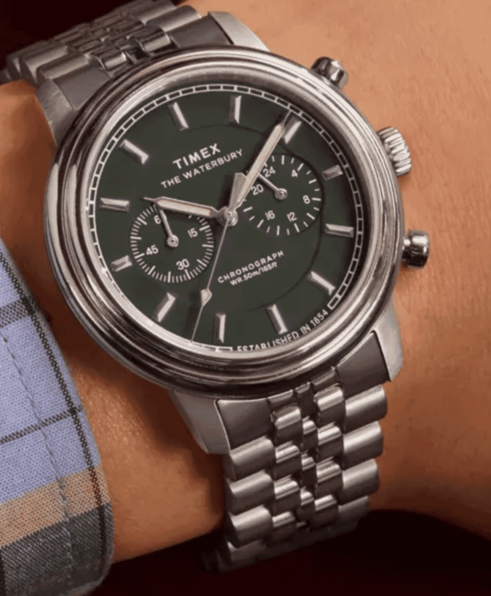 Close-up of a silver Timex chronograph watch with a green dial on a man's wrist.