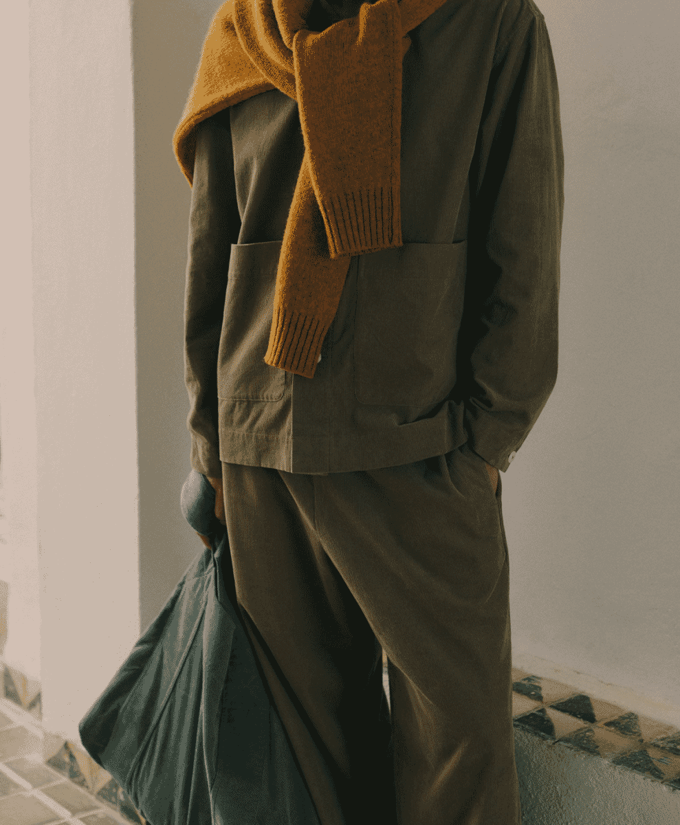 Person in a brown corduroy set with a mustard yellow knit scarf draped over the shoulders.