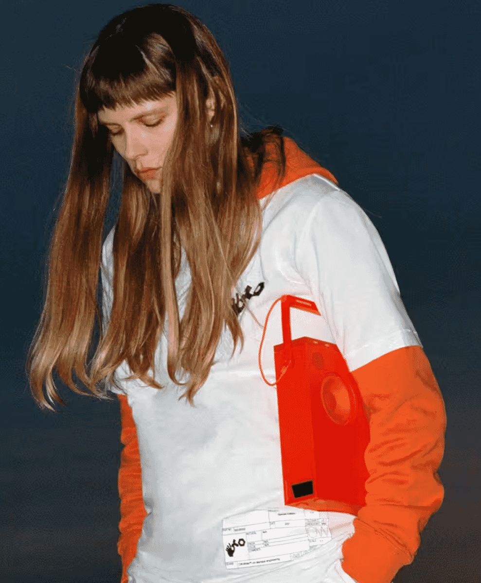 A person wearing a white and orange color-block hoodie with a red speaker graphic.