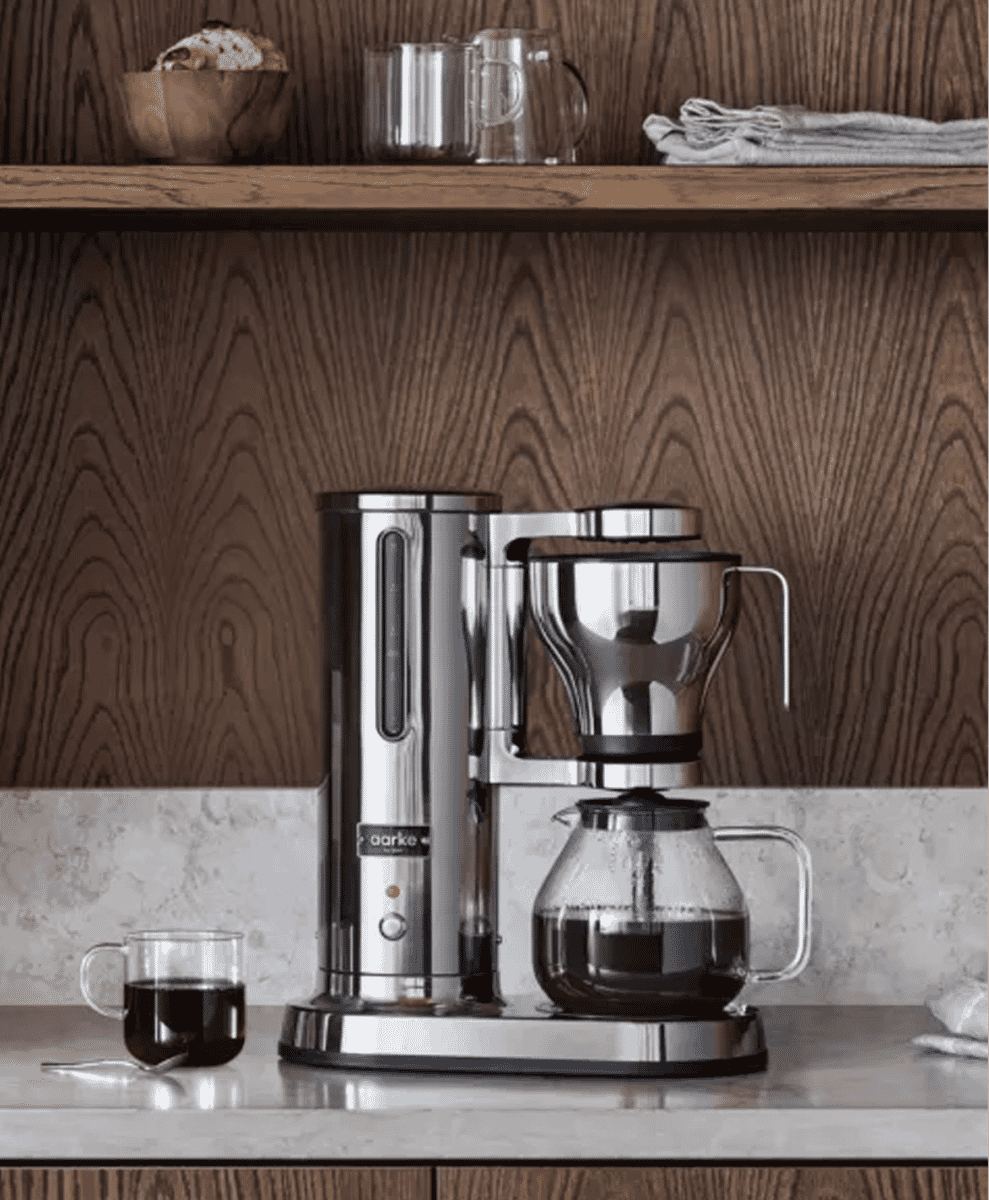 Stainless steel Aarke drip coffee maker on a marble kitchen countertop.