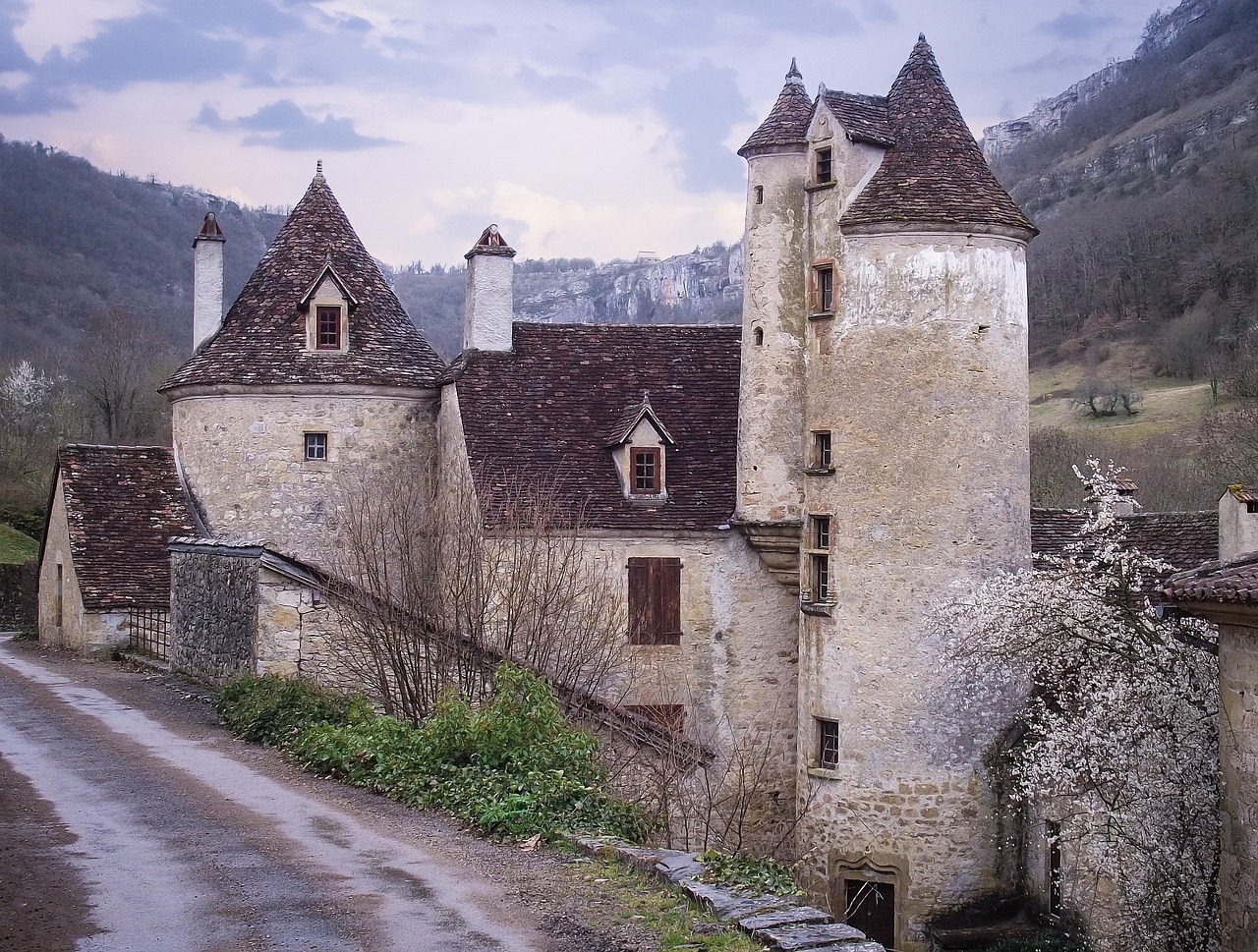 An ancient stone castle tower house with narrow windows standing in a green field.