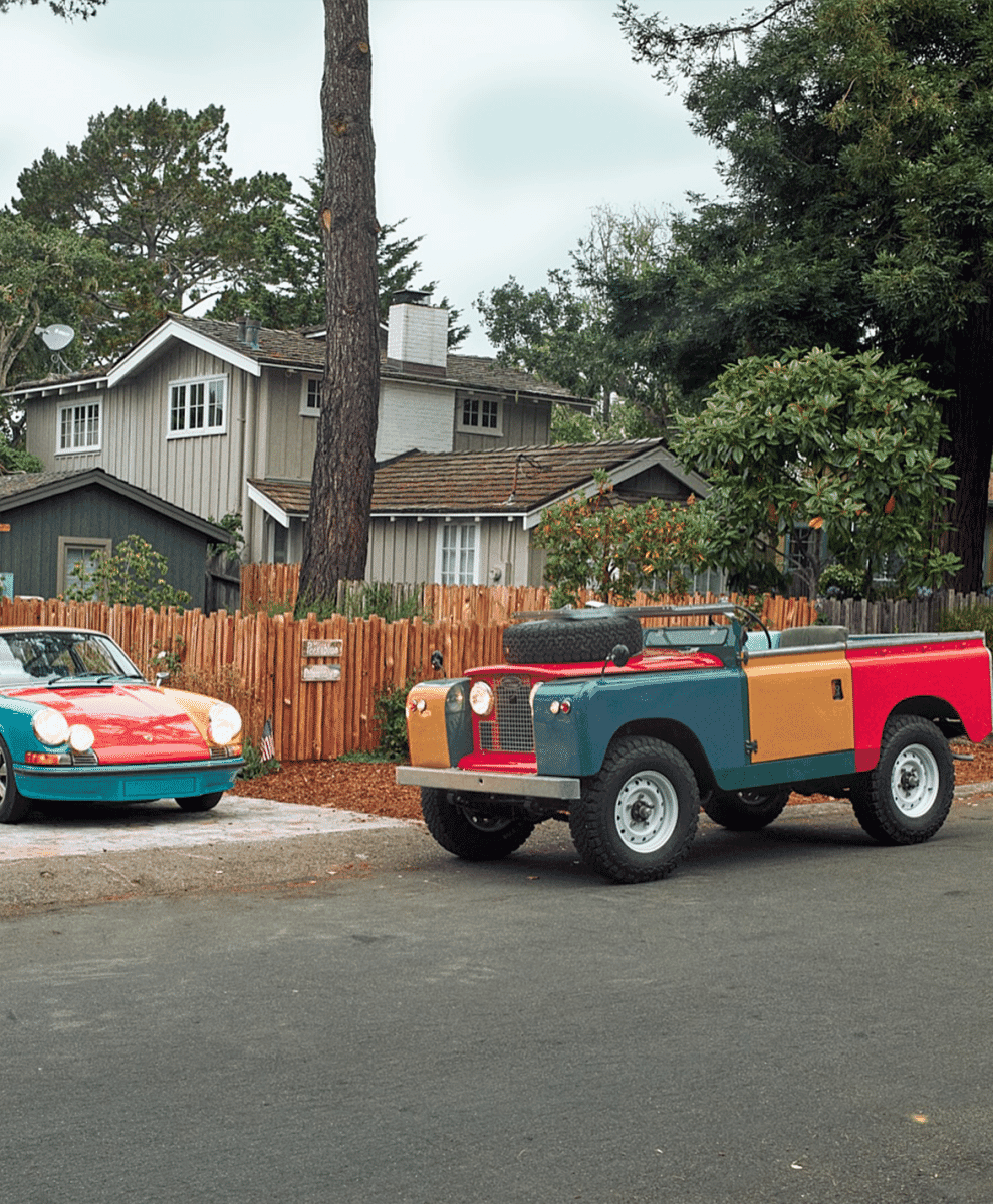 A color-blocked Land Rover and matching Porsche parked together on a suburban street.