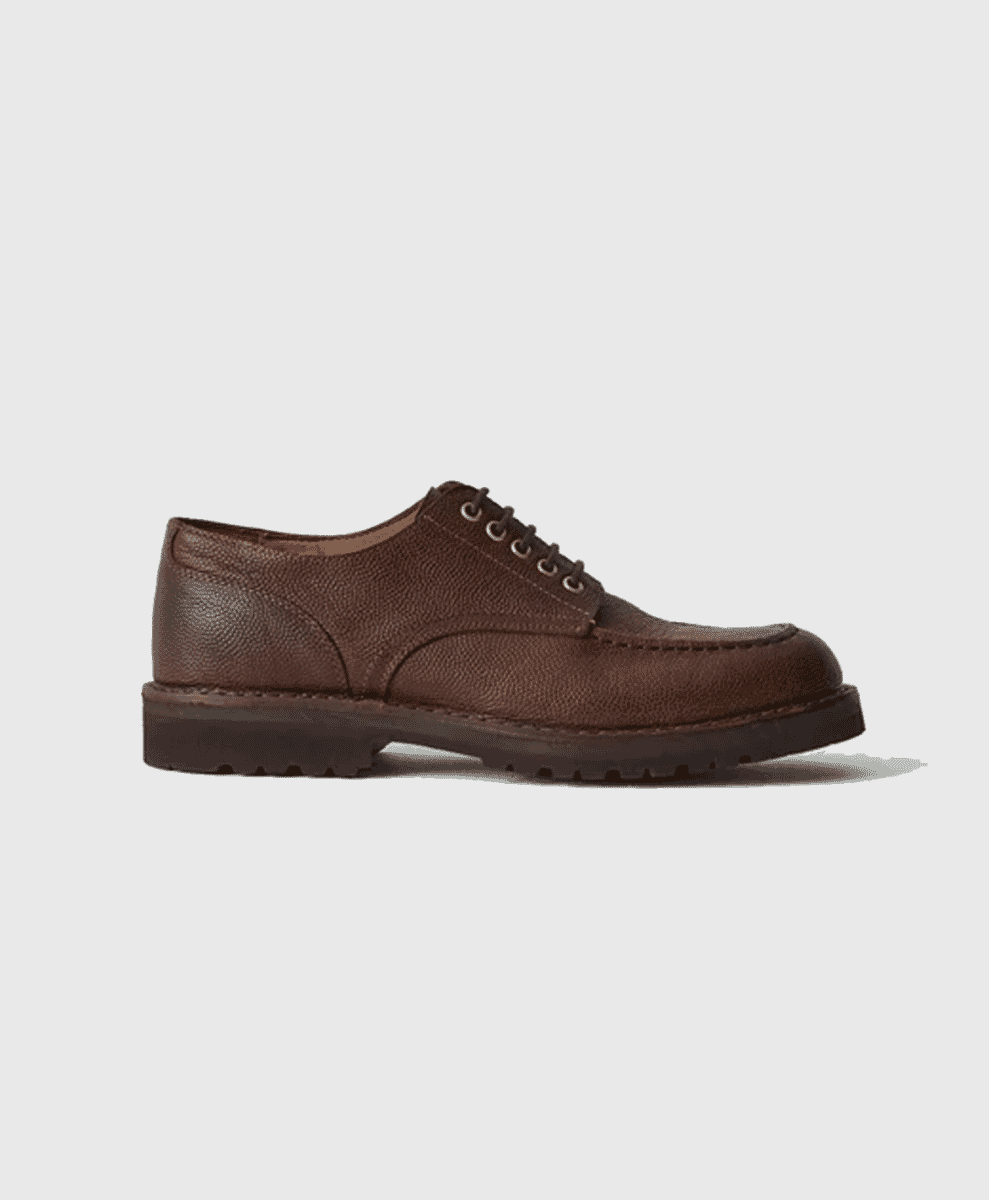 A profile shot of a brown textured leather dress shoe with a chunky black sole.