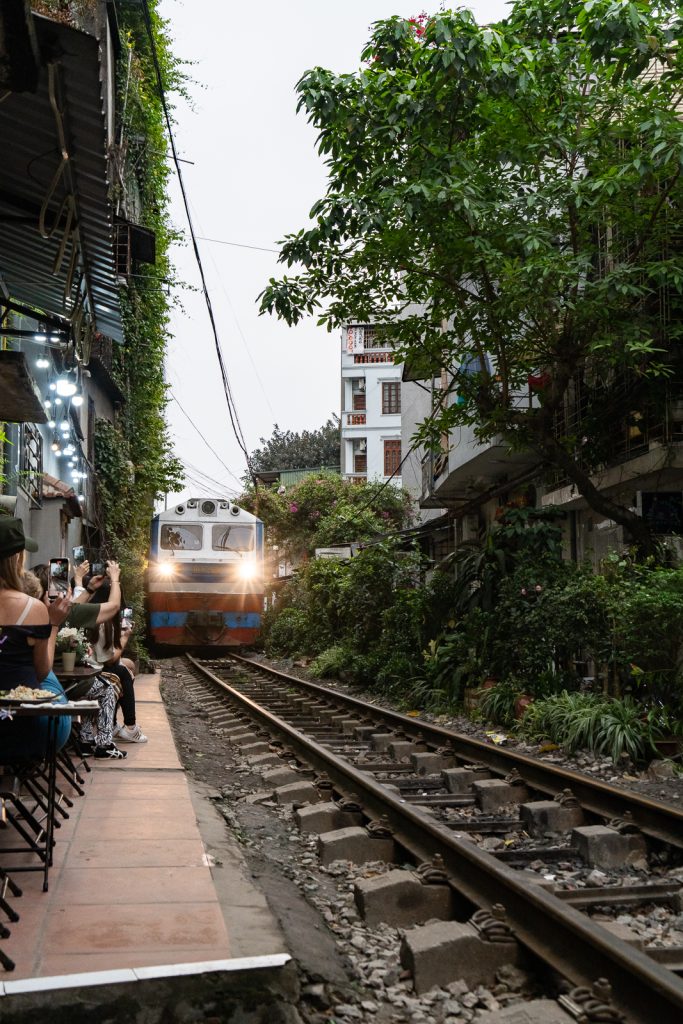 Close-up shot of a train's side panels moving rapidly past the doors of Hanoi houses.