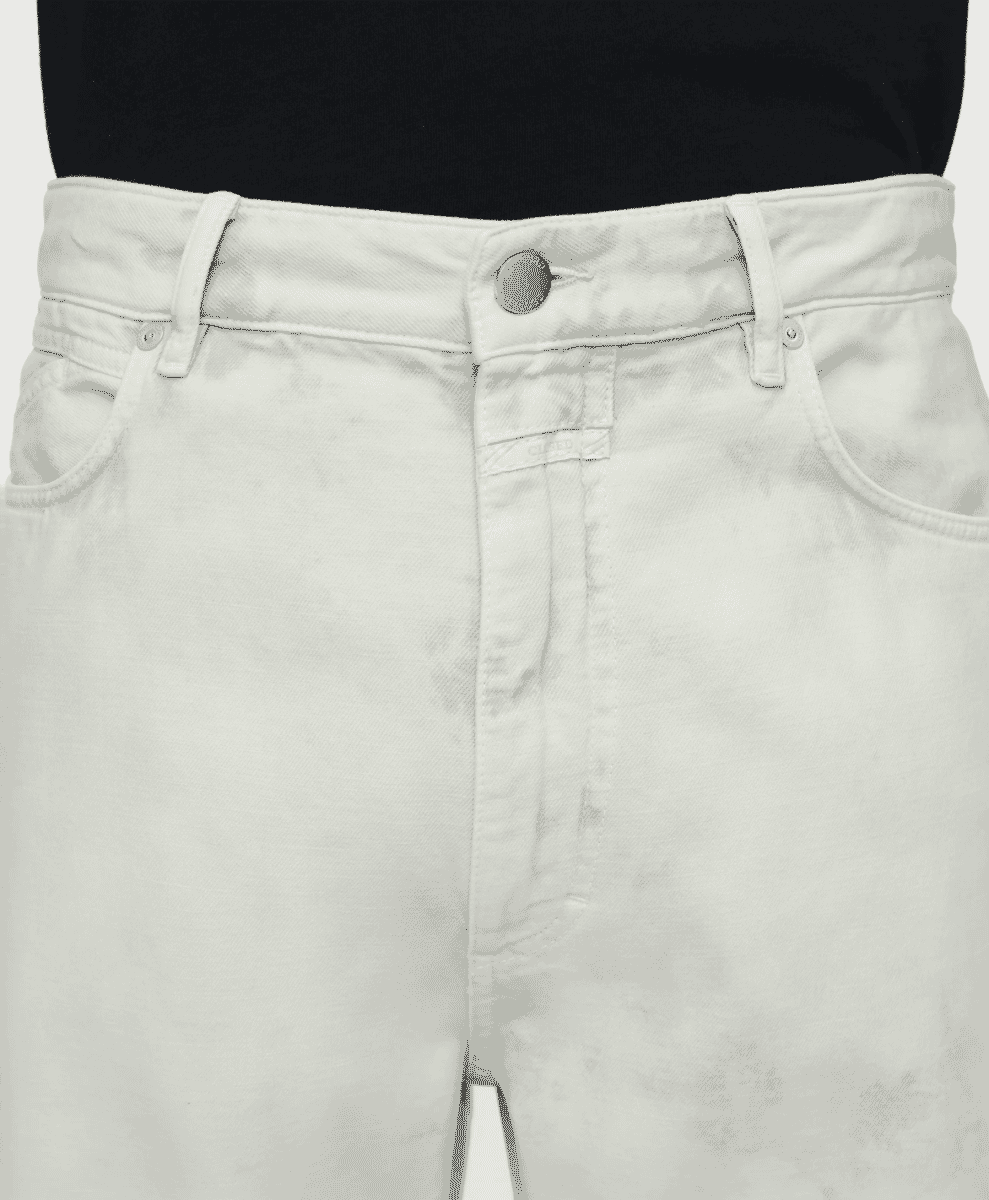 Close-up detail of off-white relaxed-fit jeans showing the buttoned waistband and fabric texture.