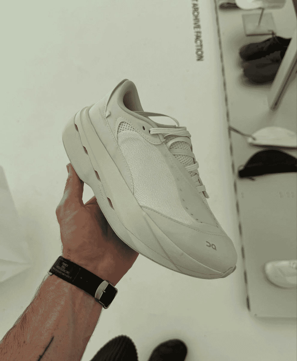 Close-up of a person holding the white ON x Post Archive Faction Cloudboom Next sneaker.