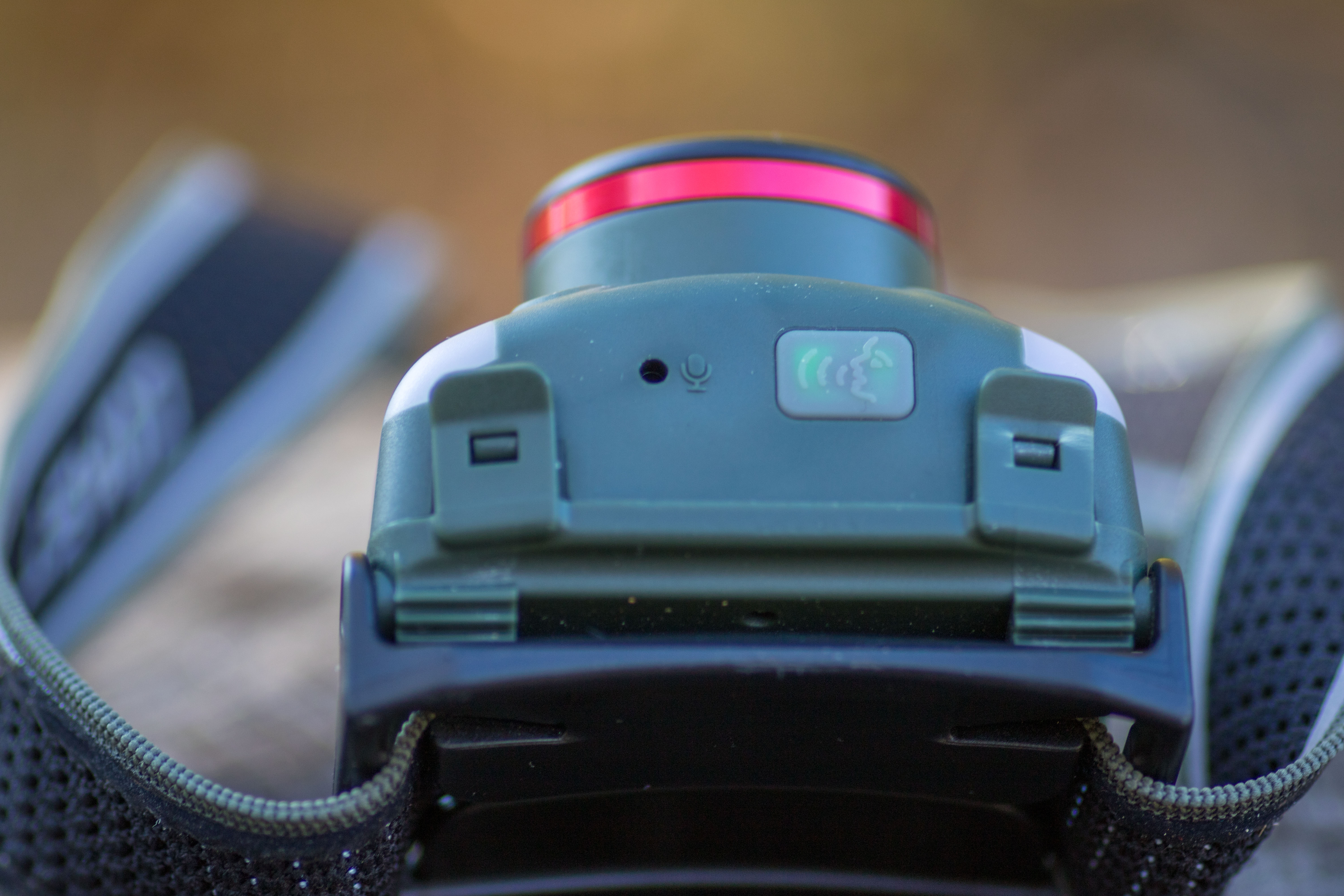 Close-up of the underside of the Coast FL97R headlamp showing a glowing blue voice command button.
